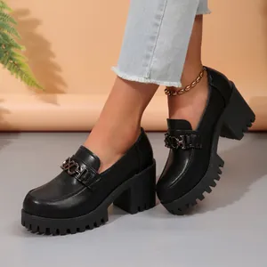 Detailopname van zwarte loafers met blokhak voor dames en een gouden ketting