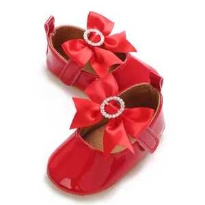 Dettaglio scarpe da principessa per neonata in vernice rossa con grandi fiocchi e strass.