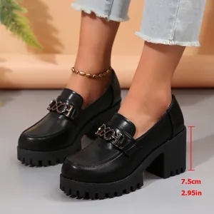 Gedetailleerd overzicht van zwarte damesloafers met blokhak, gouden ketting en plateau.