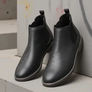 Close-up of black retro Chelsea boots with elastic side panels and stitching detail.