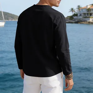 Back view of a black loose linen casual long sleeve shirt for men in a seaside setting