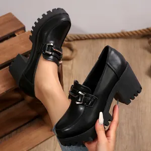 Close-up van zwarte Britse stijl platform loafers met blokhakken en metalen gesp