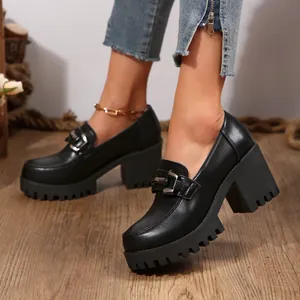 Detailweergave van zwarte platform loafers voor dames met dikke hak en gespdetail