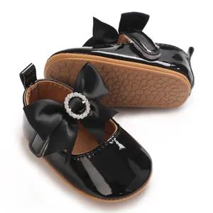 Detailed view of shiny black patent baby shoes with rhinestone bow and soft sole