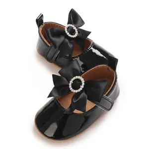 Detailed view of black patent leather infant walking shoes with a bow and rhinestone