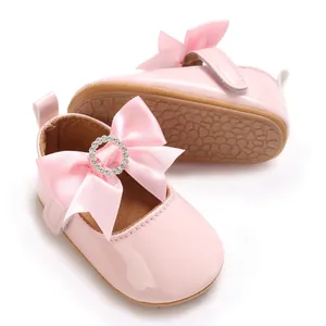 Detailed view of pink baby Mary Jane shoes with satin bow and rhinestone embellishment