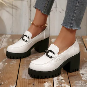 Macro-opname van witte plateau-loafers met krokodillenmotief en dikke zwarte hakken