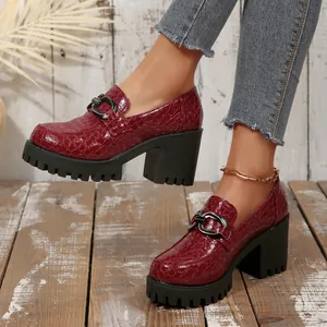 Detailweergave van wijnrode platform loafers met krokodillenprint en hoge blokhak
