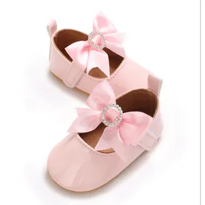 Detailed view of pink baby walking shoes with satin bow and rhinestone circle