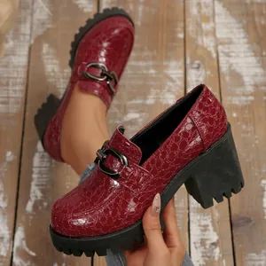 Gedetailleerde weergave van rode loafers met krokodillenprint, blokhak en metalen gesp