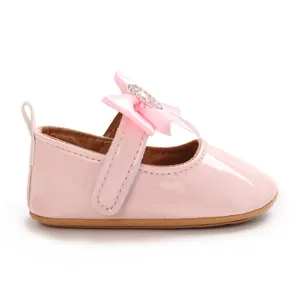 Detailed side view of pink patent leather baby walker shoe with a rhinestone bow