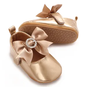 Detailed view of shiny gold infant pre-walker shoes with satin bow and non-slip sole