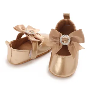 Detailed view of champagne gold baby walking shoes with large satin bow and rhinestones