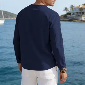 Back view of a navy blue loose linen long-sleeve T-shirt for men in a coastal setting
