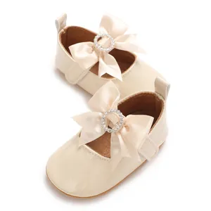 Detailed view of cream baby walker shoes with elegant silk bow and rhinestones.