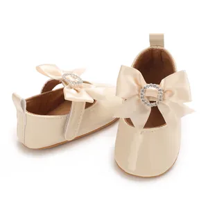 Detailed view of cream infant pre-walker shoes with satin bow and rhinestone decoration