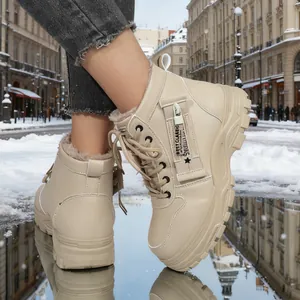 Eleganti stivali invernali beige con calda fodera in pelliccia su una strada innevata
