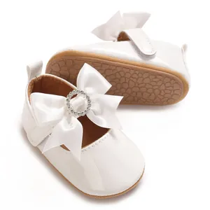 Elegant white baby girl walking shoes with a satin bow and rhinestone buckle detail.