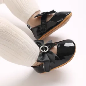Detail view of black patent leather baby shoes with bow and rhinestone buckle