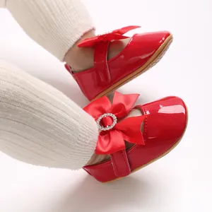 Nahaufnahme roter Lackleder-Babyschuhe mit Schleife und glänzender Strassschnalle