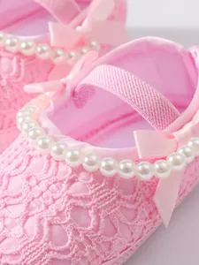 Detailaufnahme von rosa Baby-Prinzessinenschuhen mit Perlen und Satinschleifen