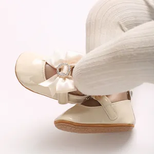 Close-up of beige baby Mary Janes featuring a silk bow with sparkling rhinestones.