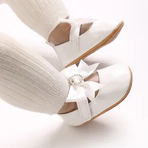 Detailed macro view of white patent leather baby walking shoes with elegant bow