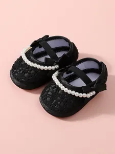 Detailansicht schwarzer Spitzen-Lauflernschuhe für Mädchen mit Perlen und Schleifen.