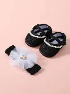 Close-up of black baby girl princess shoes and matching pearl flower headband set
