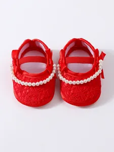 Detaillierte Draufsicht auf rote Baby-Prinzessin-Schuhe mit Perlenriemen und Spitze