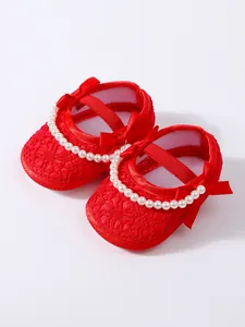 Detailansicht der roten Spitzen-Babyschuhe mit eleganten Perlen- und Schleifenakzenten