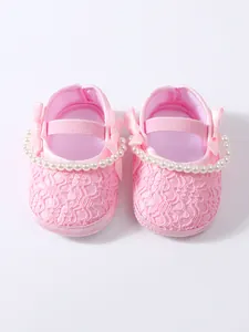 Nahaufnahme von rosa Baby-Prinzessin-Schuhen mit edler Spitze und Perlenriemen