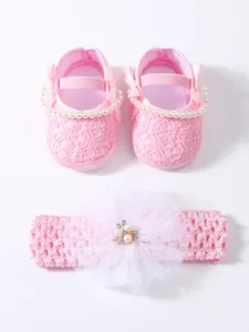 Close-up view of pink lace baby princess shoes and matching floral headband set
