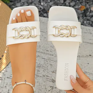 Close-up view of elegant white flat slide sandals featuring a metal chain buckle