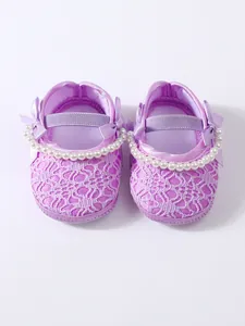 Detailansicht von Baby-Prinzessinenschuhen mit lila Spitze, Perlen und Schleifendekoration
