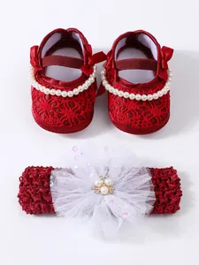 Detail view of red lace baby princess shoes and matching pearl flower headband set