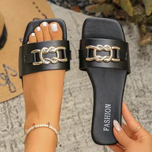 Close-up of black summer flat sandals featuring an elegant interlocking gold metal chain