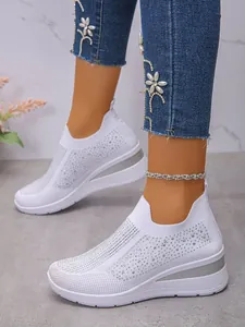 Detail der atmungsaktiven weißen Keilsneaker aus Strick mit funkelnden Strasssteinen