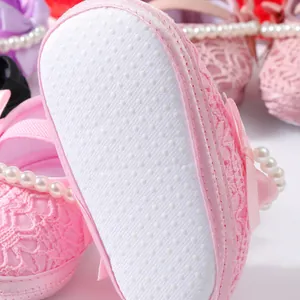 Nahaufnahme von rosa Baby-Prinzessinenschuhen aus Spitze mit Perlenriemen