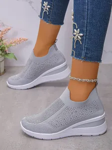 Nahaufnahme grauer Fly-Knit Sneaker mit Strasssteinen und Keilabsatz Schuhe
