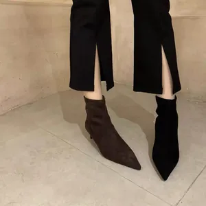 Detailansicht spitzer Stöckelabsatz-Stiefeletten aus schwarzem und braunem Wildleder.