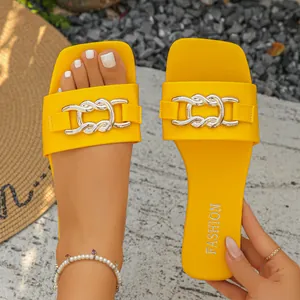 Close-up of yellow flat slide sandals with decorative silver metal chain link detail