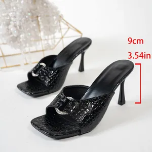 Mules élégantes en similicuir croco noir à bout carré, talon aiguille et boucle cristal.