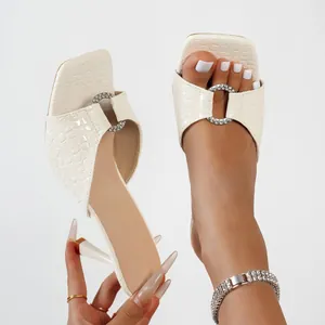 Vue détaillée de mules à talons aiguilles blanches gaufrées croco avec anneau en diamant.