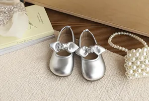 Silver girl's princess shoes with a large metallic bow decoration on a soft sole base.
