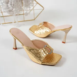 Détail de mules élégantes à talons hauts en or avec motif crocodile et boucle strass