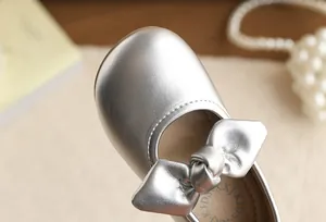 Close-up of a metallic silver girl's princess shoe with a delicate bow detail.