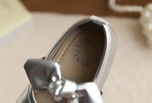 Detailed macro view of silver girl's princess shoe with a decorative bow and soft lining.