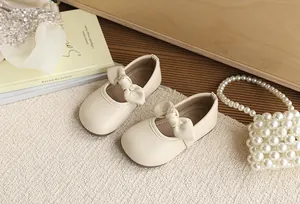 Elegant beige girls' Mary Jane shoes featuring bow detail on a cream textured rug