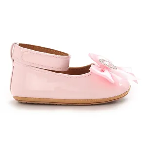 Gros plan d'une chaussure de princesse rose pour bébé avec nœud en soie et strass en cœur